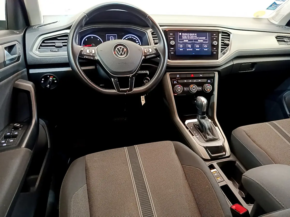 Vue intérieure avant du Volkswagen T-Roc 2.0 TDI blanc, avec volant multifonction, écran tactile et levier de boîte automatique.