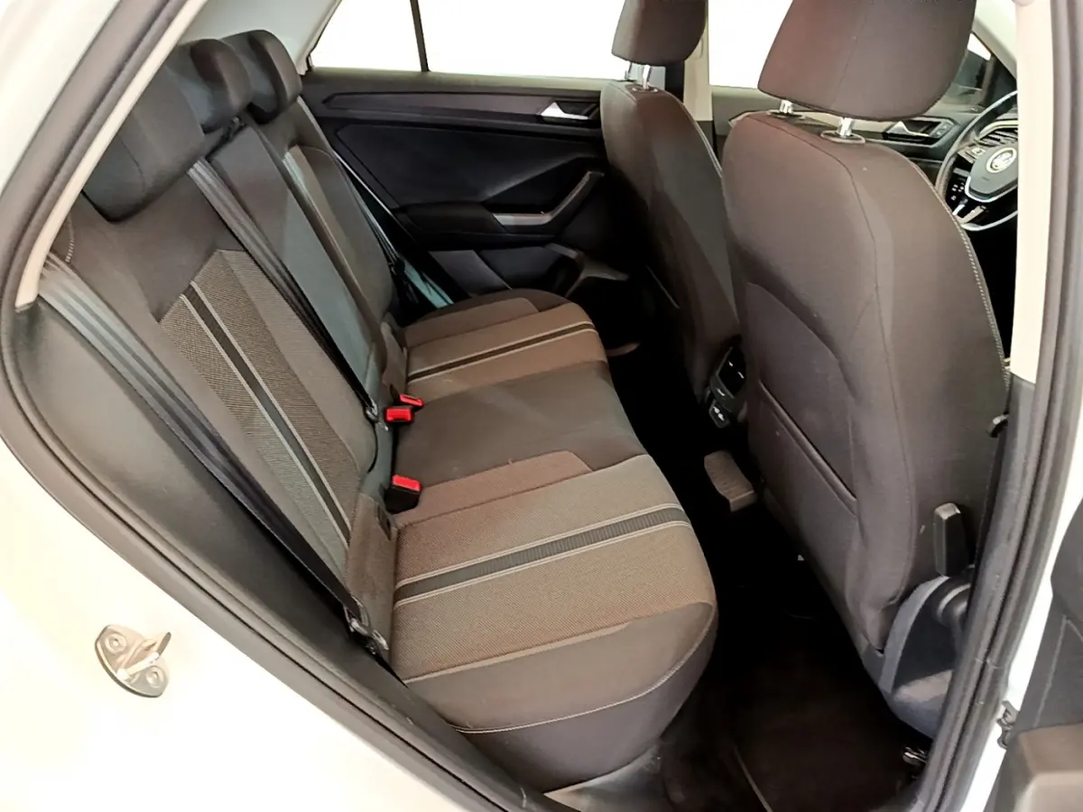 Vue intérieure côté gauche sur la banquette arrière noire du Volkswagen T-Roc blanc, avec sièges tissu et appuie-têtes.