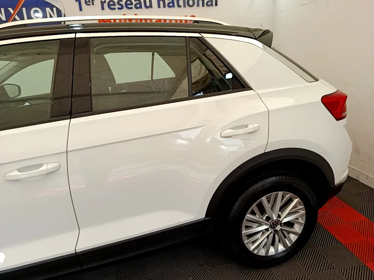 Vue latérale côté droit du Volkswagen T-Roc blanc, mettant en valeur la porte arrière et la roue arrière avec jante alliage.