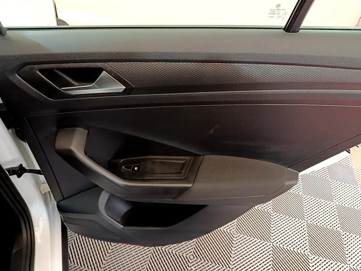 Vue côté gauche de la porte intérieure noire du Volkswagen T-Roc blanc avec poignée et commande de vitre électrique.