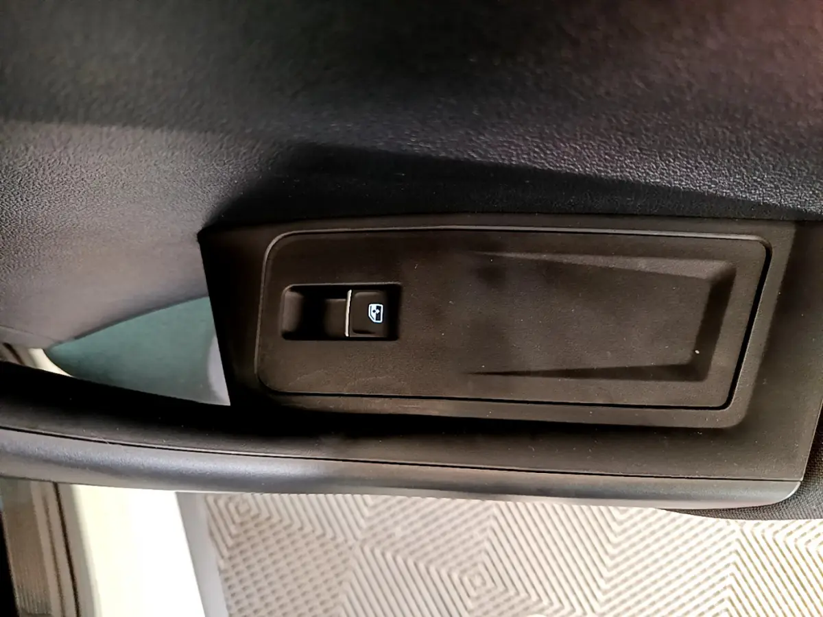 Gros plan sur la commande de lève-vitre côté conducteur du Volkswagen T-Roc blanc, intérieur noir.