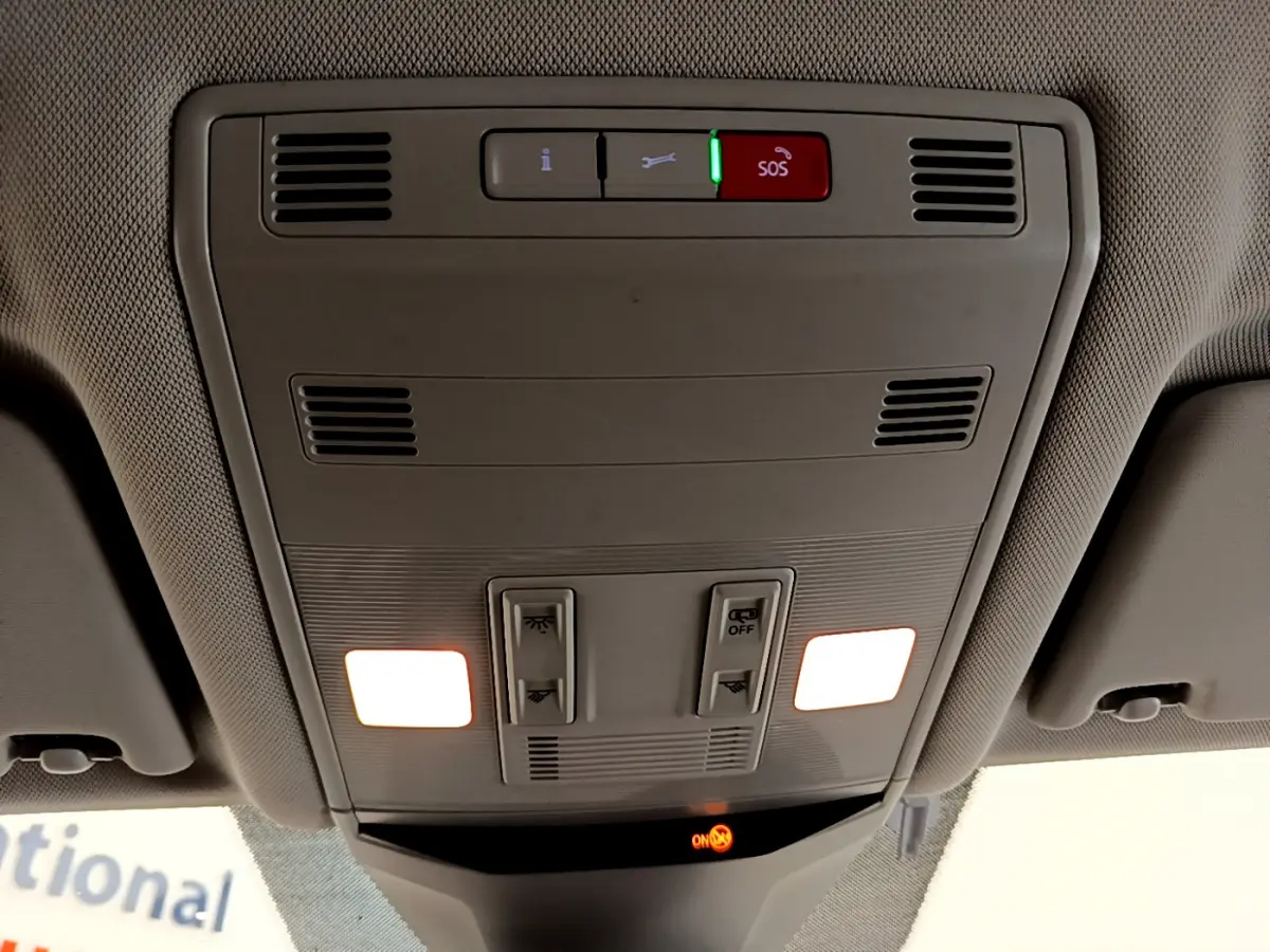 Vue intérieure du plafonnier avant du Volkswagen T-Roc blanc 2021 avec éclairage et bouton SOS activé.