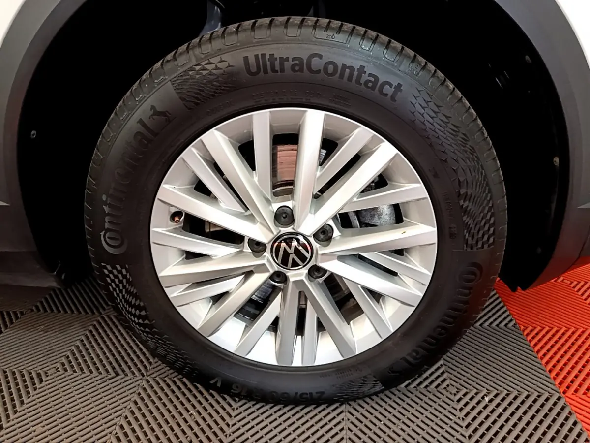 Gros plan sur la jante argentée en alliage du Volkswagen T-Roc blanc, mettant en valeur le logo VW central.