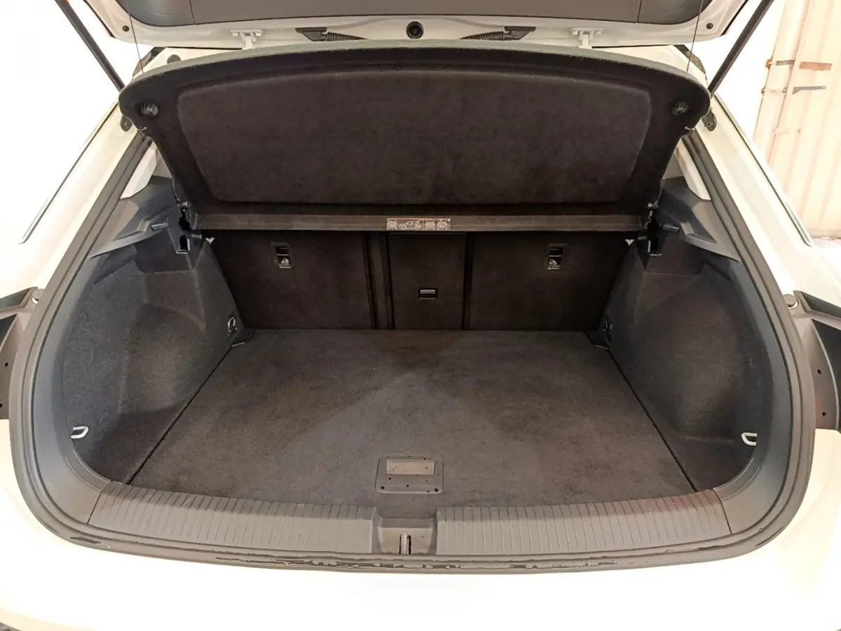 Coffre ouvert du Volkswagen T-Roc blanc 2021, vue arrière montrant l’espace de chargement et la tablette de séparation.