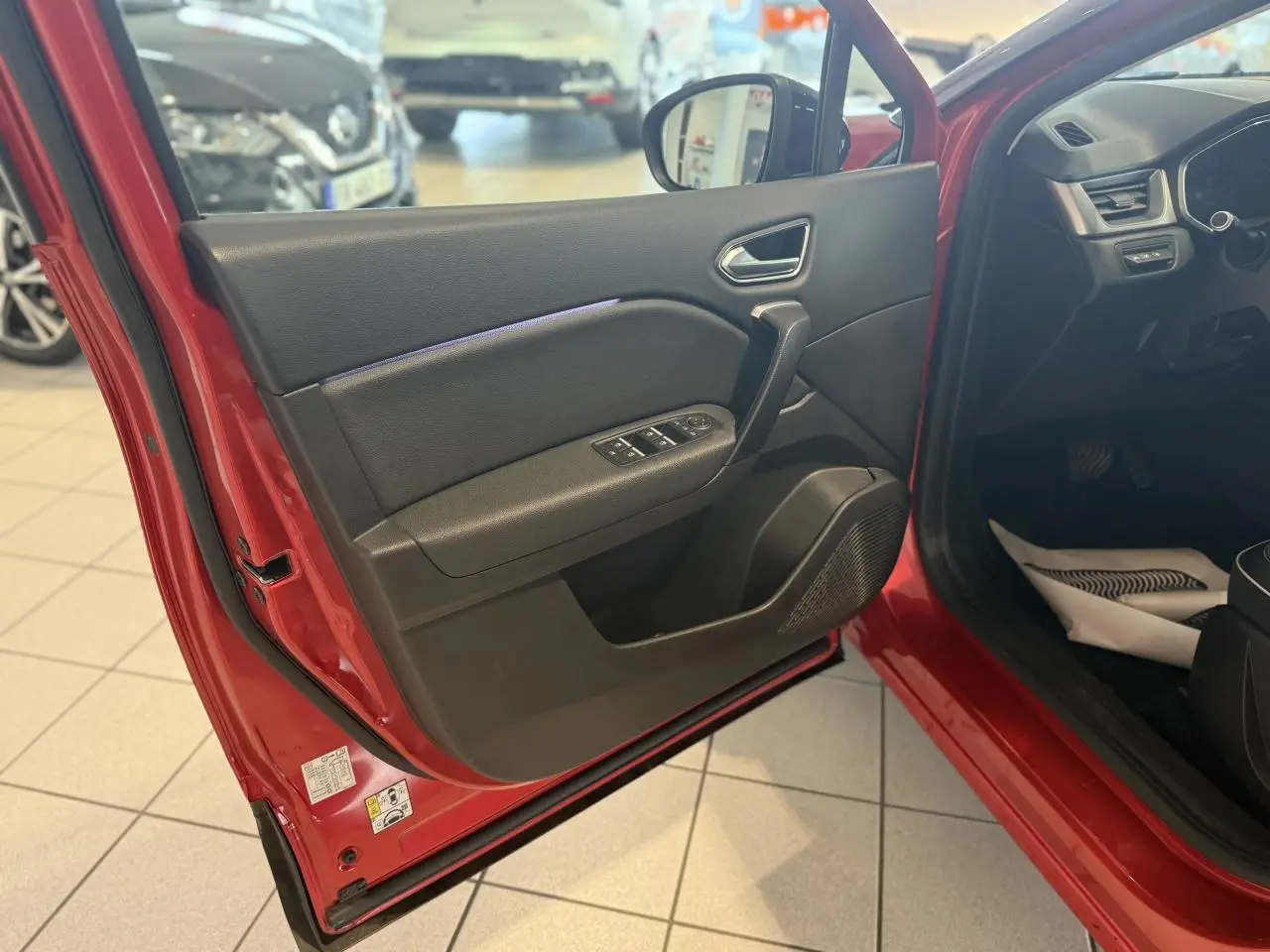Vue intérieure de la porte avant gauche rouge foncé du Renault Captur 2020 avec commandes de vitres et rétroviseur.