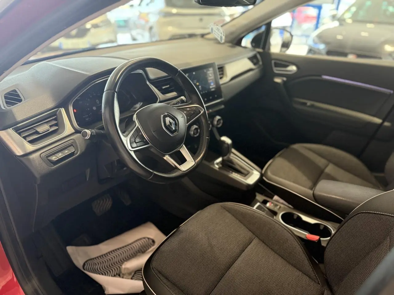 Vue intérieure côté conducteur du Renault Captur 2020, avec volant cuir, console centrale et sièges tissu noirs.