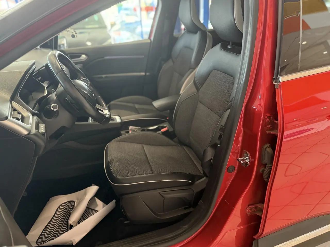 Vue intérieure côté conducteur du Renault Captur rouge foncé 2020, sièges tissu et cuir noirs visibles.