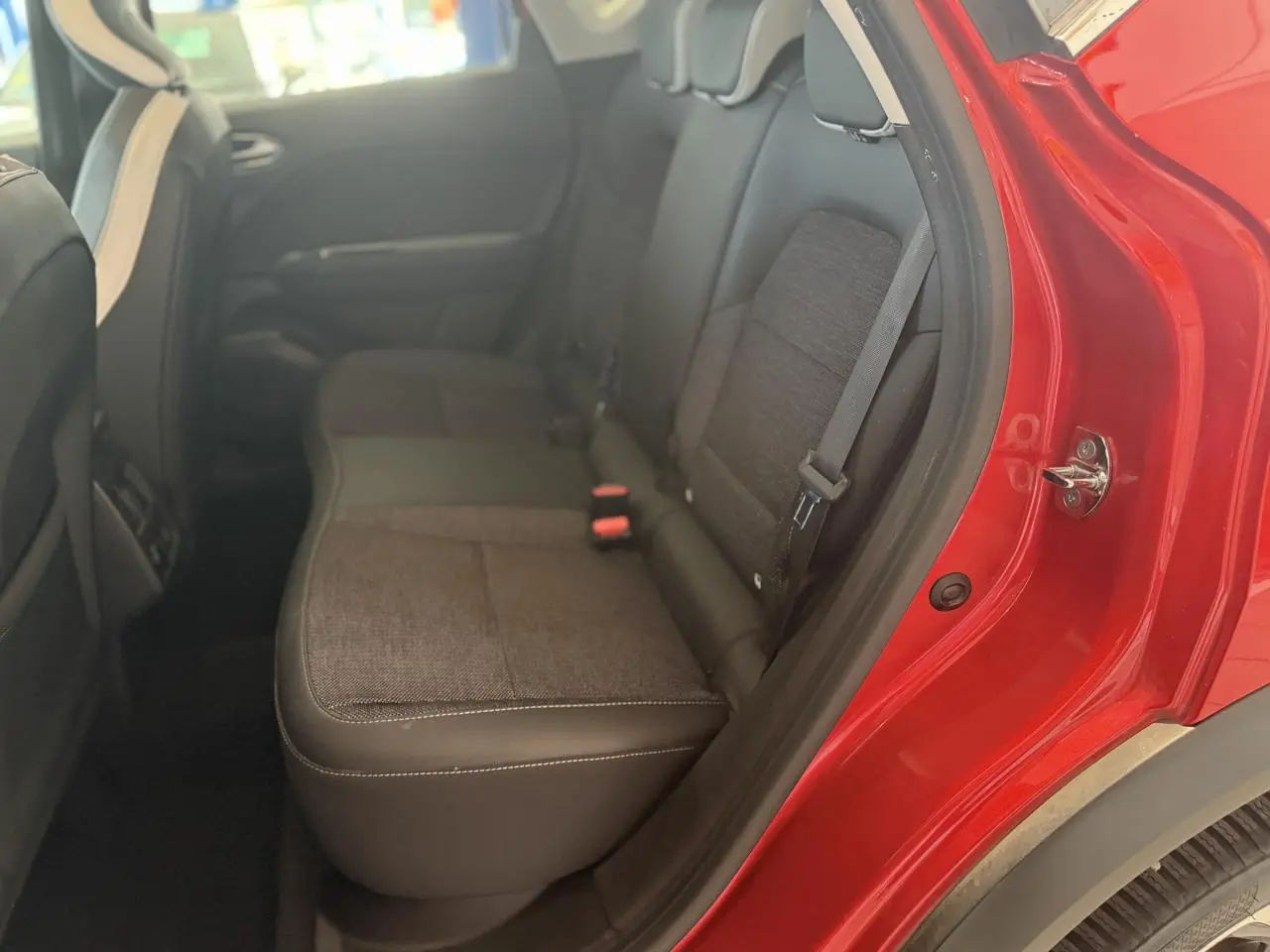 Vue intérieure côté arrière droit du Renault Captur 2020 rouge foncé, montrant les sièges arrière en tissu gris et noir.