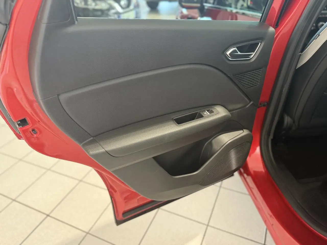 Porte arrière gauche ouverte du Renault Captur rouge foncé 2020, montrant la garniture intérieure noire et les commandes de fenêtre.