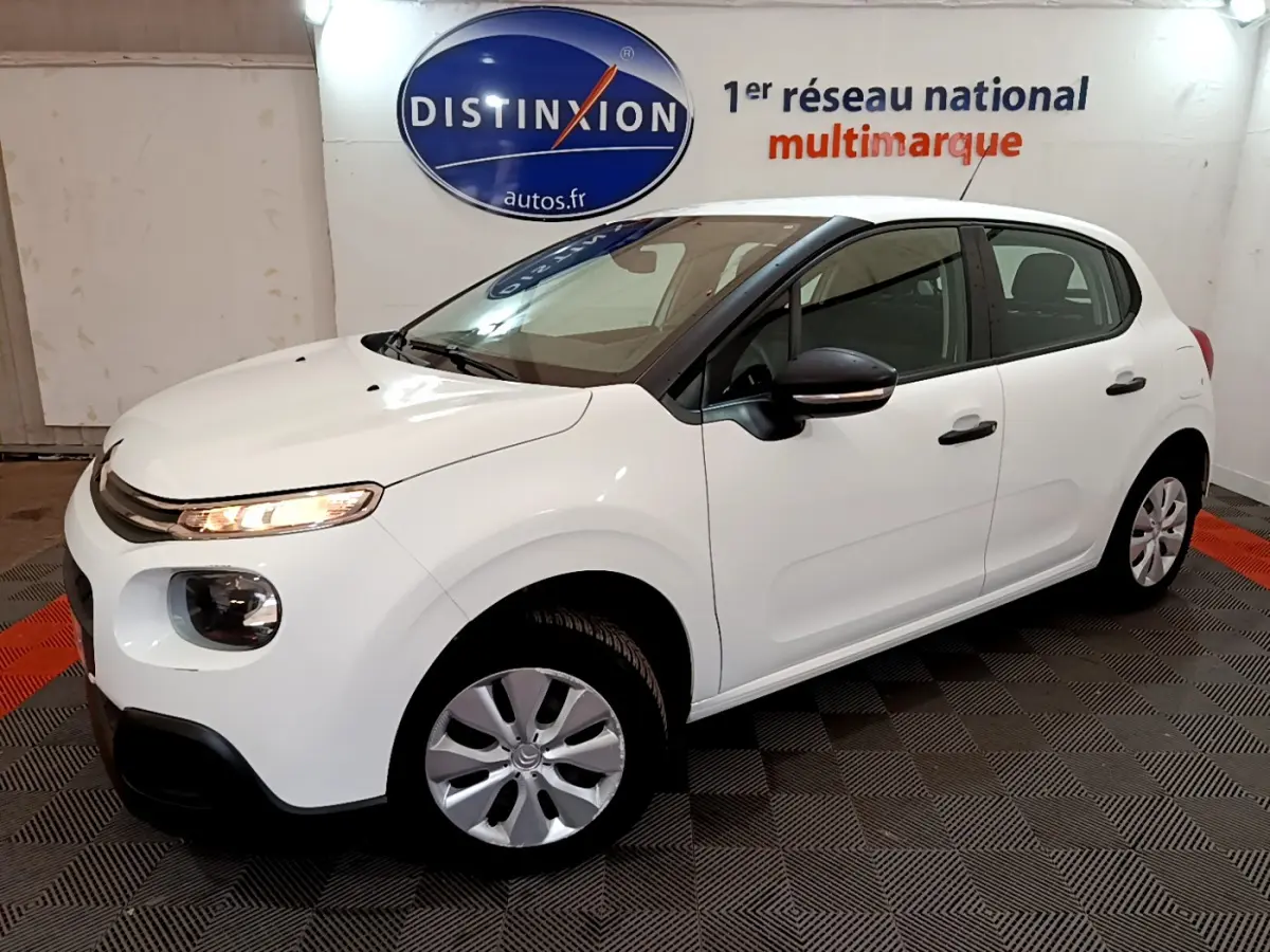 Citroën C3 blanche vue en 3/4 avant droit, avec phares allumés et jantes alliage simple.