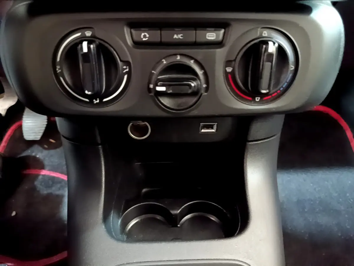 Vue rapprochée de la console centrale noire de la Citroën C3 avec commandes de climatisation et prises USB et 12V.