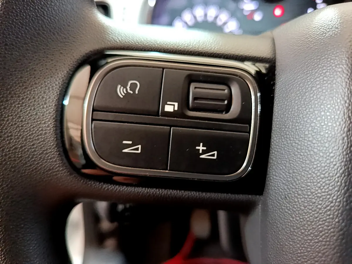 Gros plan sur les commandes noires du volant de la Citroën C3 PureTech 68 BVM Live, avec boutons de volume et appel.