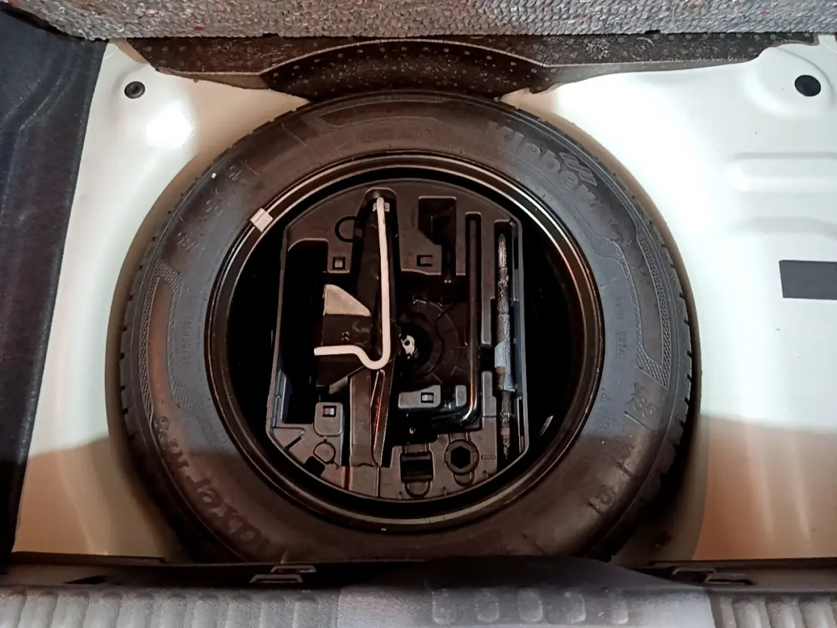 Vue plongeante sur la roue de secours noire dans le coffre blanc d'une Citroën C3 PureTech 68 BVM Live 2018.