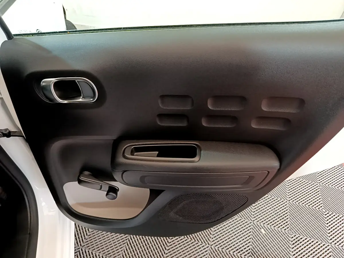 Vue rapprochée de la porte arrière gauche blanche d’une Citroën C3 2018, avec poignée et manivelle de vitre noire.