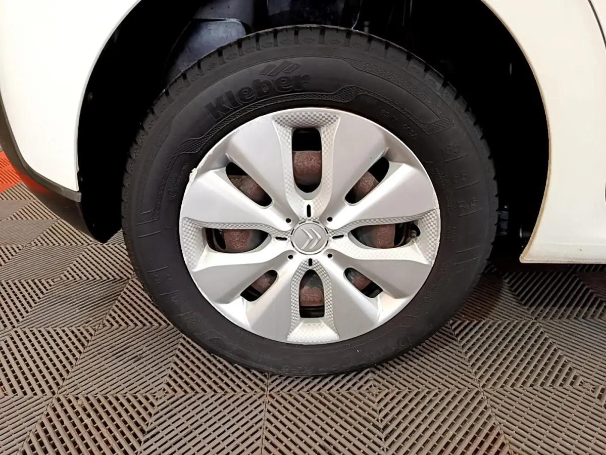 Gros plan sur la roue avant gauche d'une Citroën C3 blanche avec enjoliveur au design moderne.