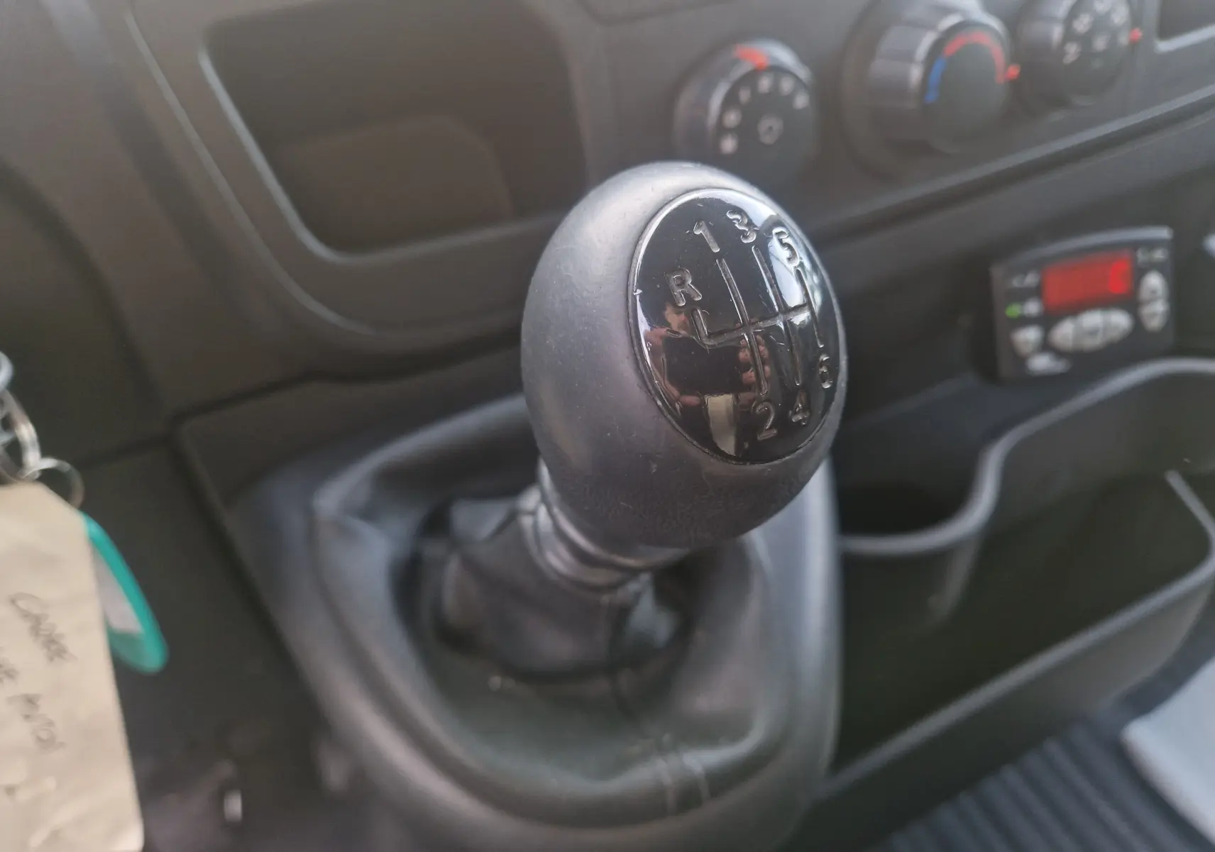Gros plan sur le levier de vitesses manuel noir du Renault Master Plancher Cabine, avec commandes de climatisation en arrière-plan.