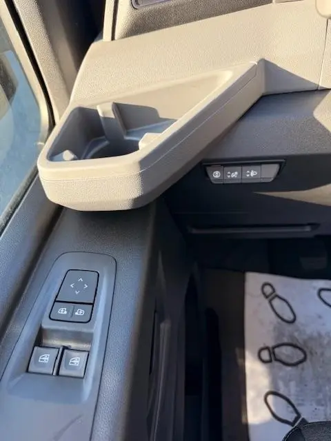 Détail intérieur côté conducteur du Renault Master blanc 2025, montrant les commandes de vitres et les boutons d'assistance sur la portière.