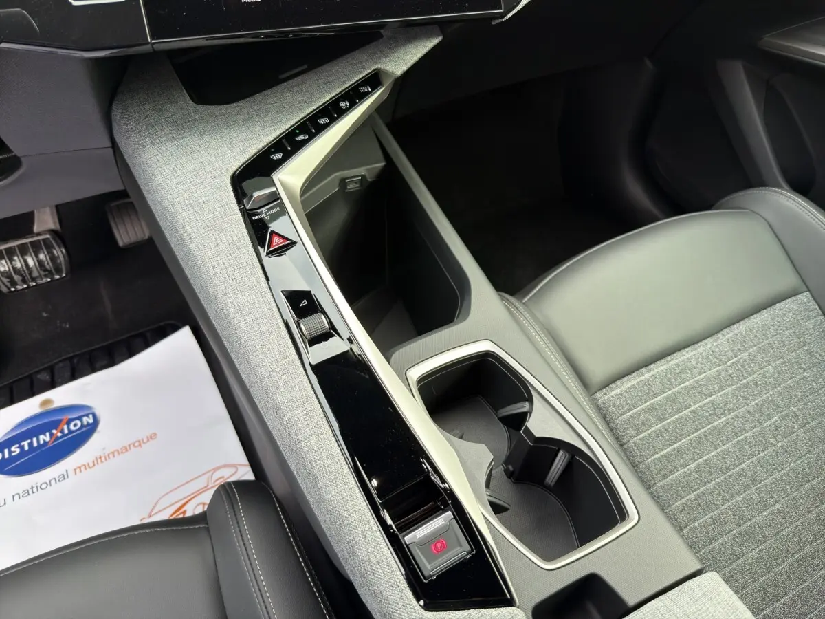 Vue intérieure rapprochée du console central gris clair et noir avec sièges tissu et cuir gris du Peugeot 3008 blanc 2025.