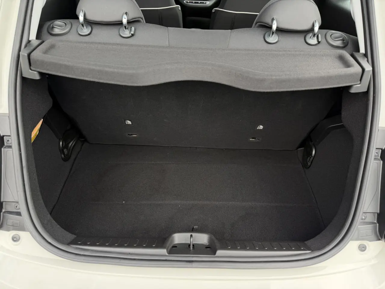 Coffre ouvert vu de l'arrière d'une FIAT 500 électrique blanche Arctic, montrant l'espace de chargement et la plage arrière.