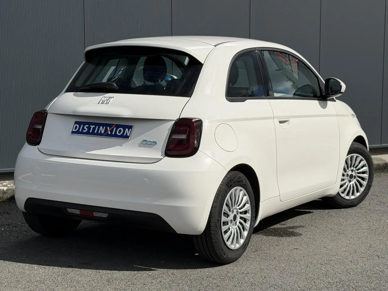 Vue 3/4 arrière droite de la FIAT 500 électrique blanche Arctic avec jantes alu 16 pouces et feux arrière foncés.
