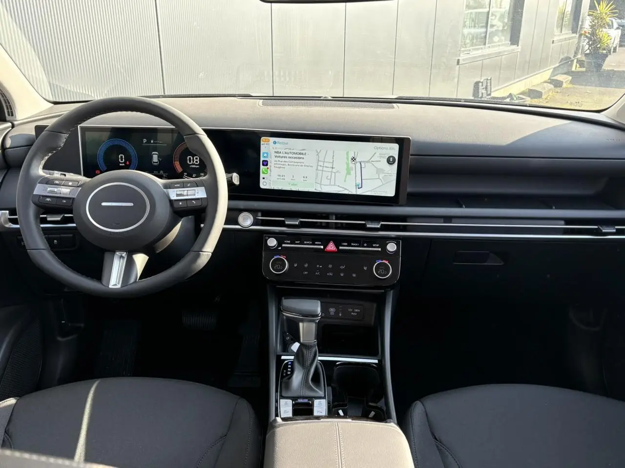 Intérieur du Hyundai Tucson 2025 vu de face, tableau de bord noir avec écran tactile large et volant cuir noir.