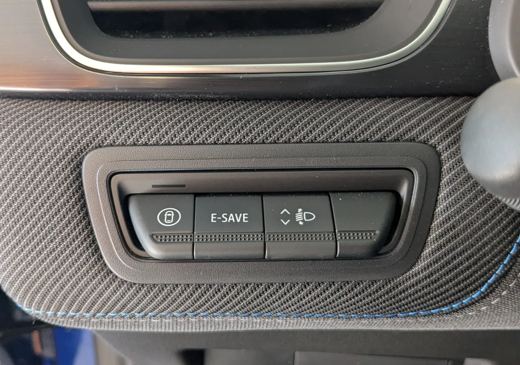 Gros plan sur les boutons de commande E-SAVE et réglage des phares, sur la console intérieure du Renault Symbioz bleu iron.