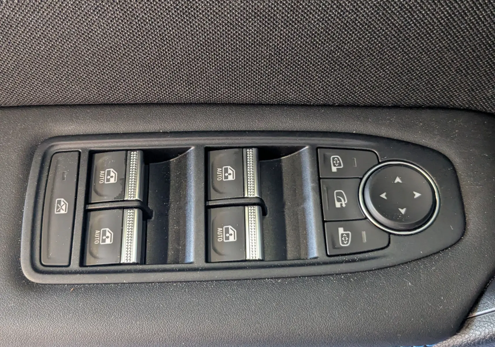 Panneau de commandes des vitres électriques et rétroviseurs sur la porte intérieure d'une Renault Symbioz bleu Iron.