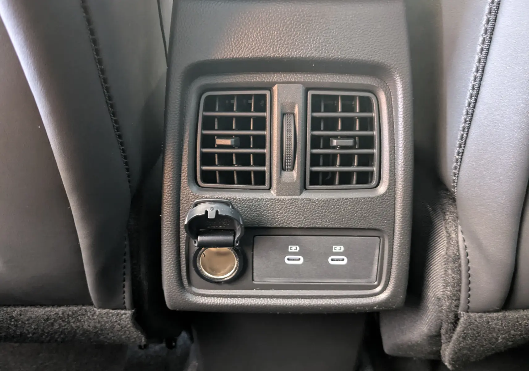 Détail de la console arrière avec prises USB et prise 12V entre les sièges noirs du Renault Symbioz E-Tech Hybrid 2025.