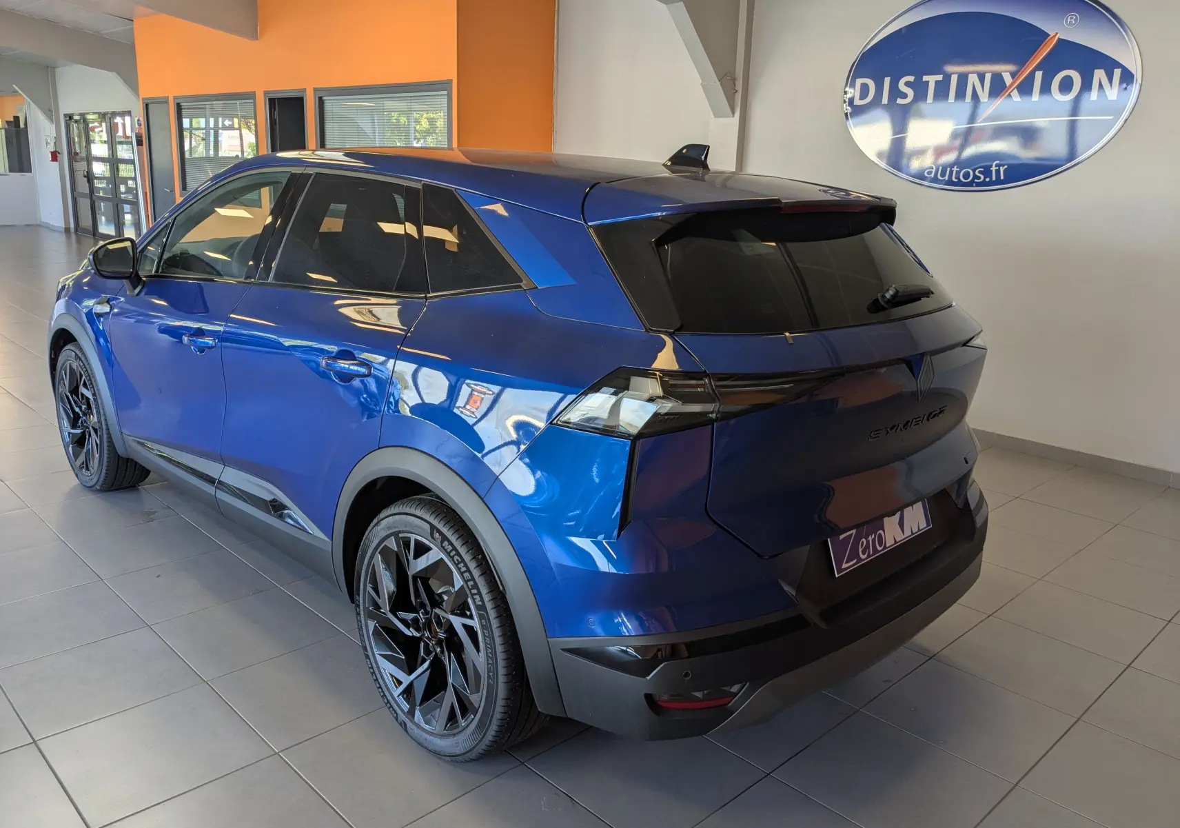 Vue 3/4 arrière droite du Renault SYMBIOZ bleu iron avec jantes noires et vitres teintées en showroom.
