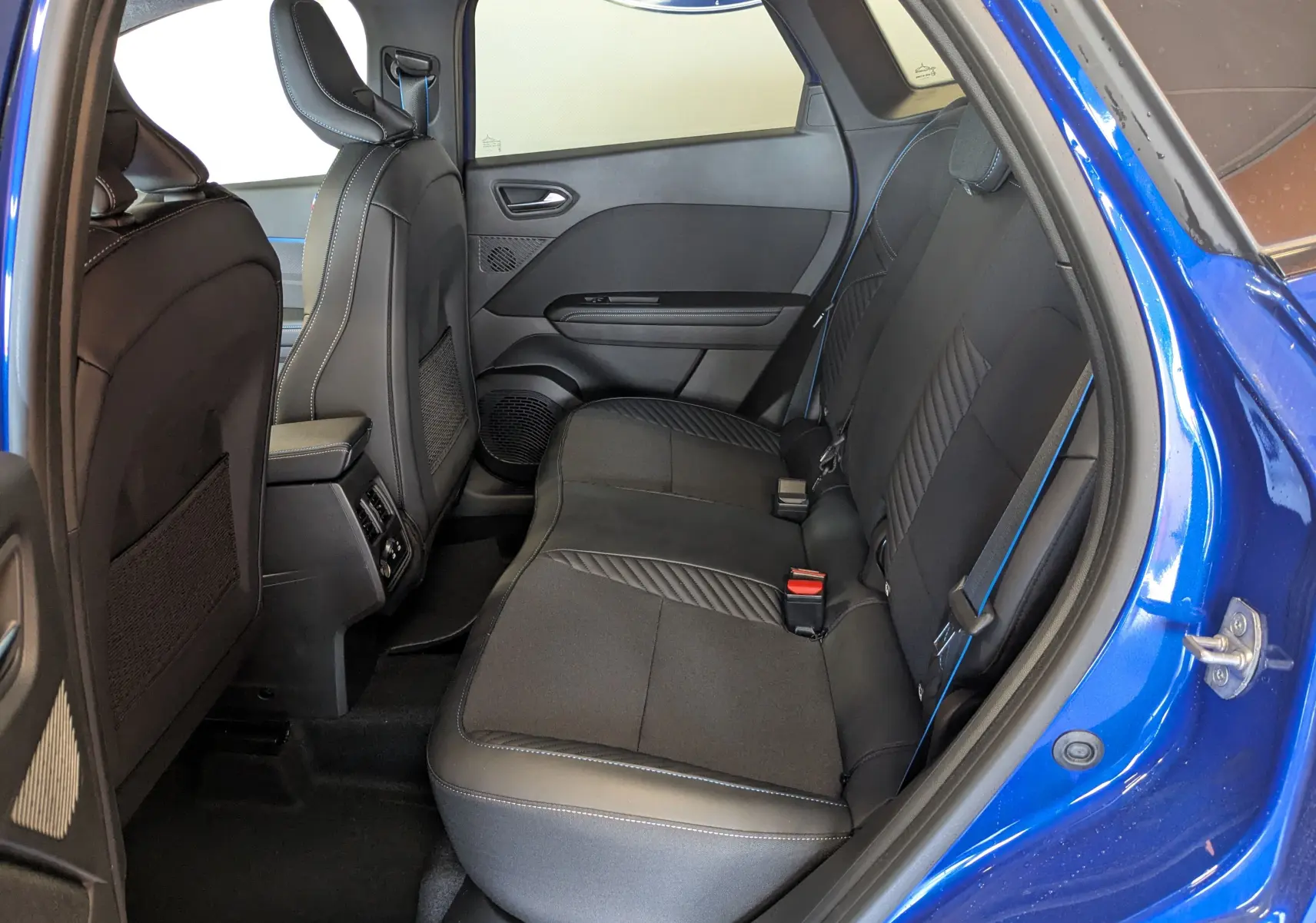 Vue intérieure côté droit sur la banquette arrière noire avec surpiqûres bleues du Renault Symbioz E-Tech Full Hybrid 2025 bleu Iron.