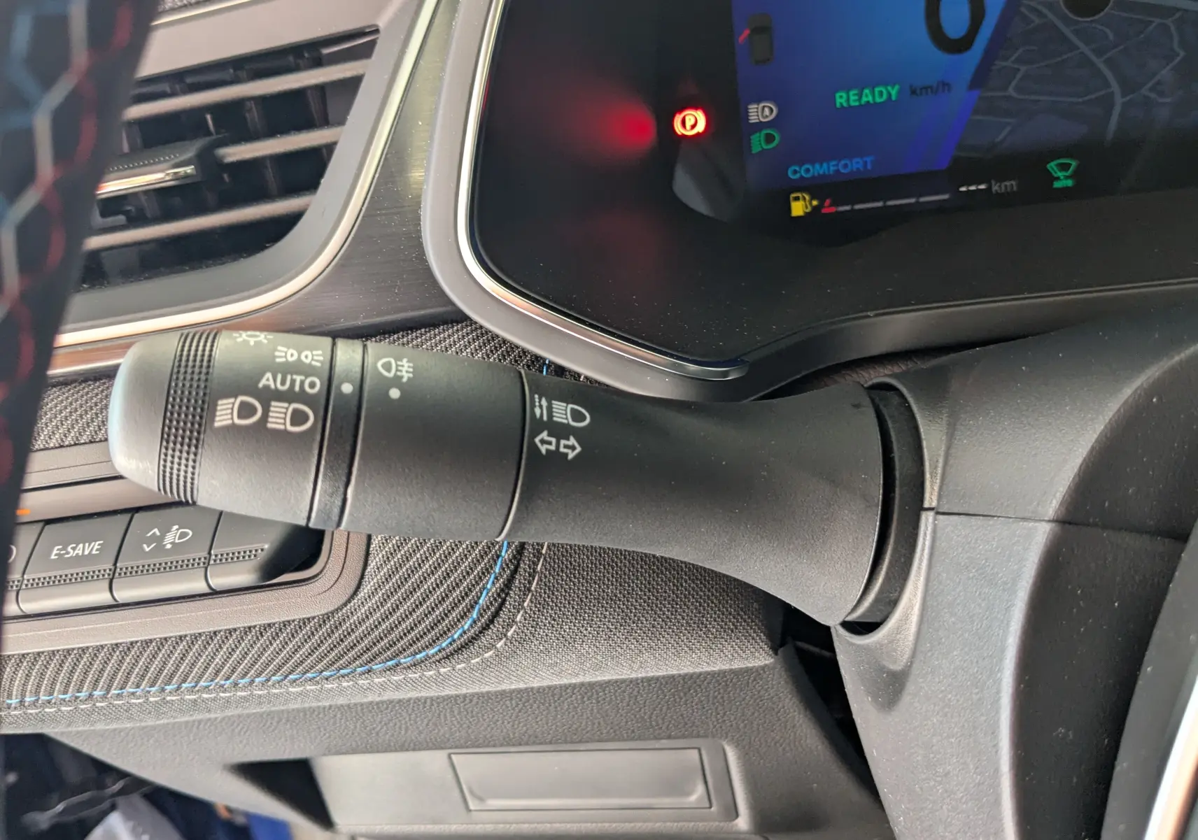 Gros plan sur la commande des feux et clignotants à gauche du volant dans l'habitacle du Renault Symbioz bleu Iron 2025.