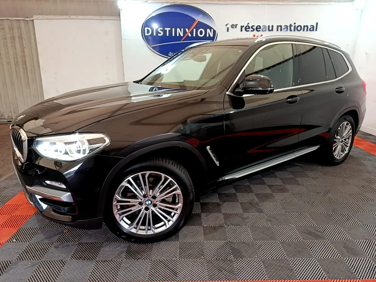 BMW X3 xDrive20d noir en 3/4 avant droit avec jantes alliage et phares LED allumés en intérieur showroom.