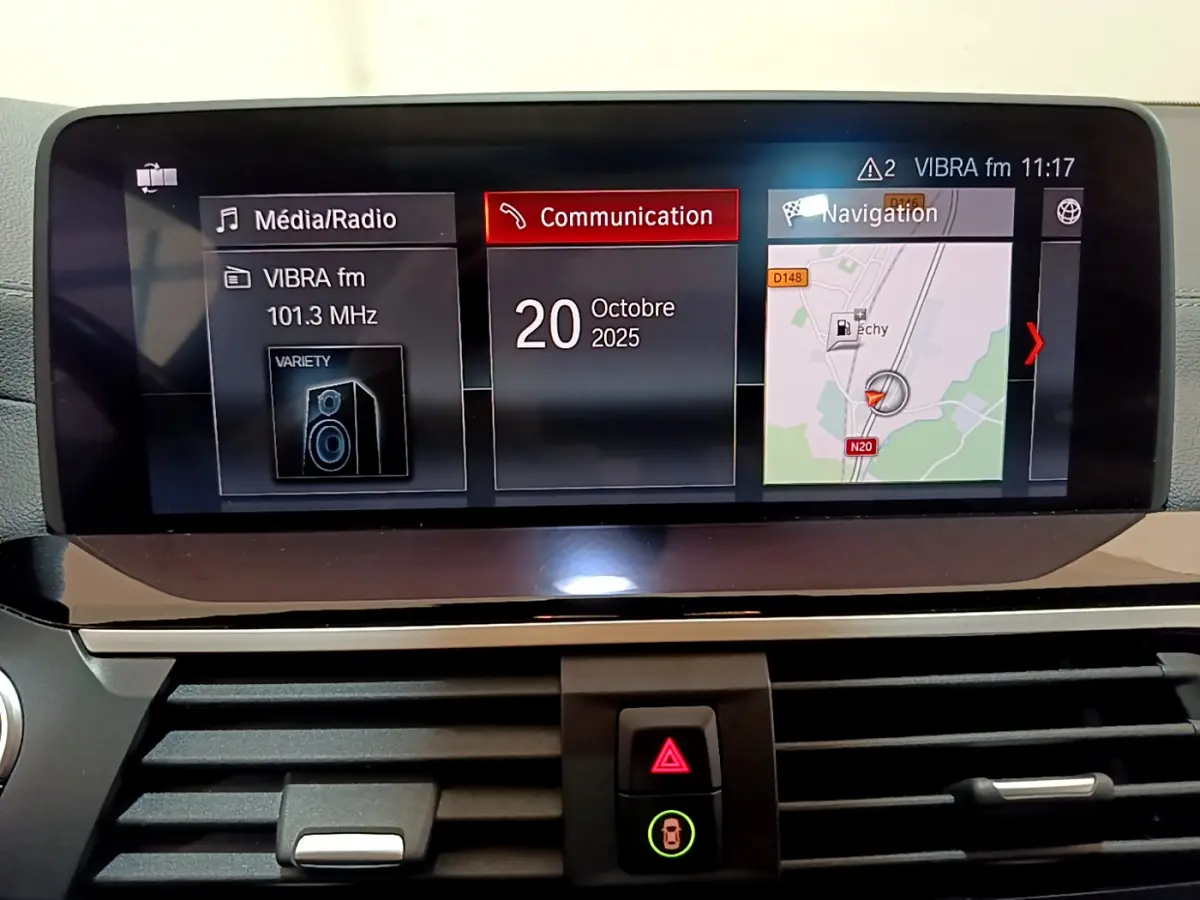 Écran tactile central du tableau de bord du BMW X3 noir, affichant radio, communication et navigation.