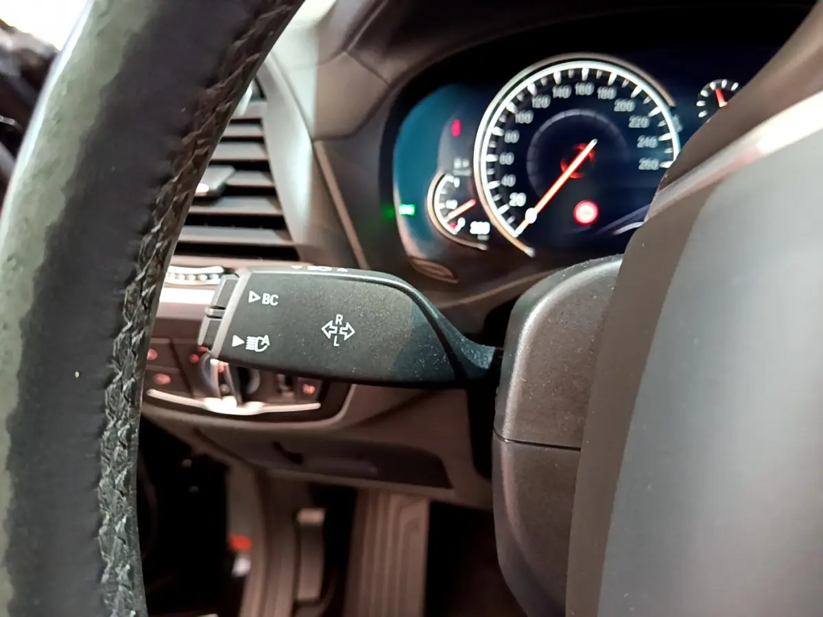 Vue rapprochée du commodo gauche et du tableau de bord éclairé du BMW X3 noir, version 2019 Luxury.