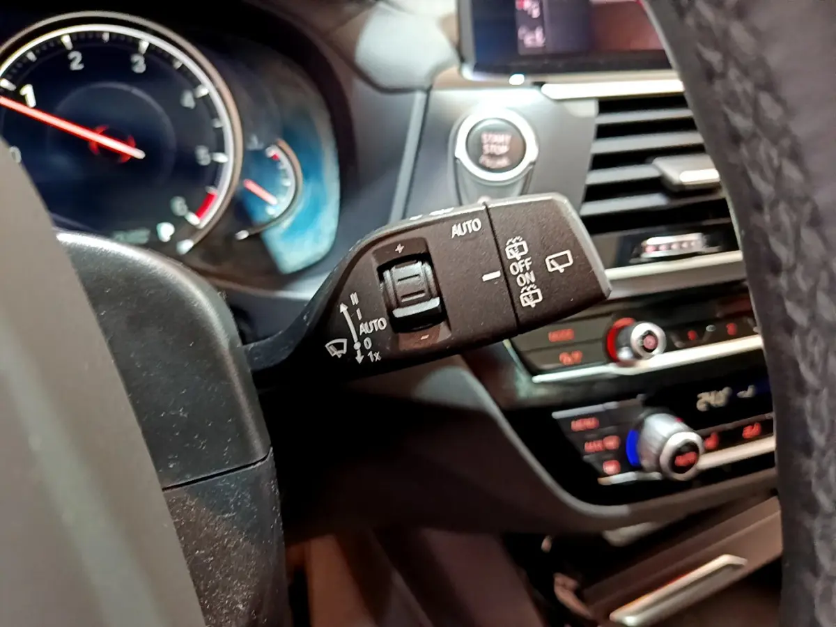 Gros plan sur la commande d’essuie-glace à gauche du volant dans l’habitacle noir d’une BMW X3 2019.