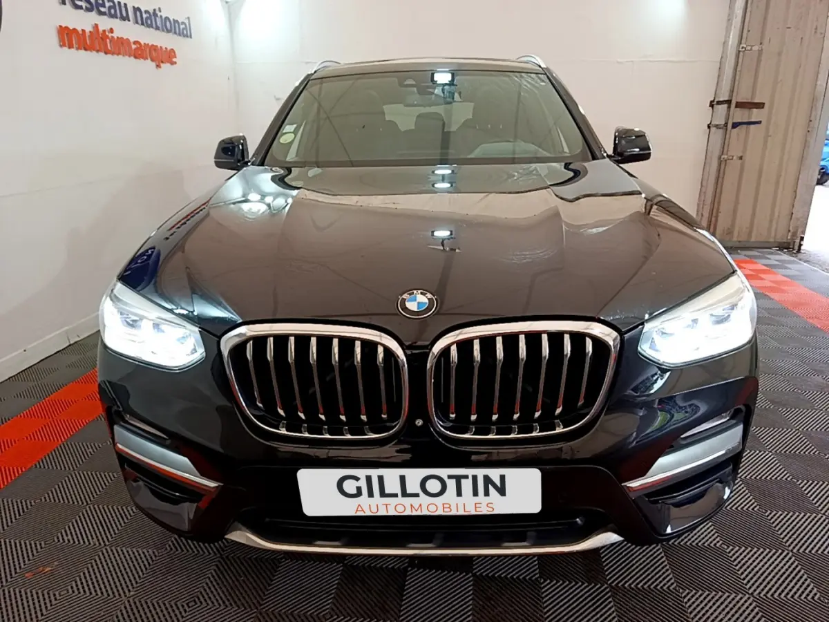 Vue avant d'un BMW X3 noir 2019 avec phares LED allumés et calandre chromée distinctive.