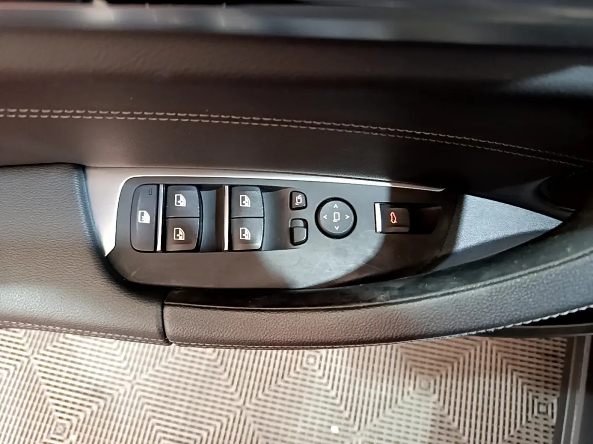 Vue rapprochée des commandes de lève-vitres et rétroviseurs sur la porte côté gauche d’un BMW X3 noir.