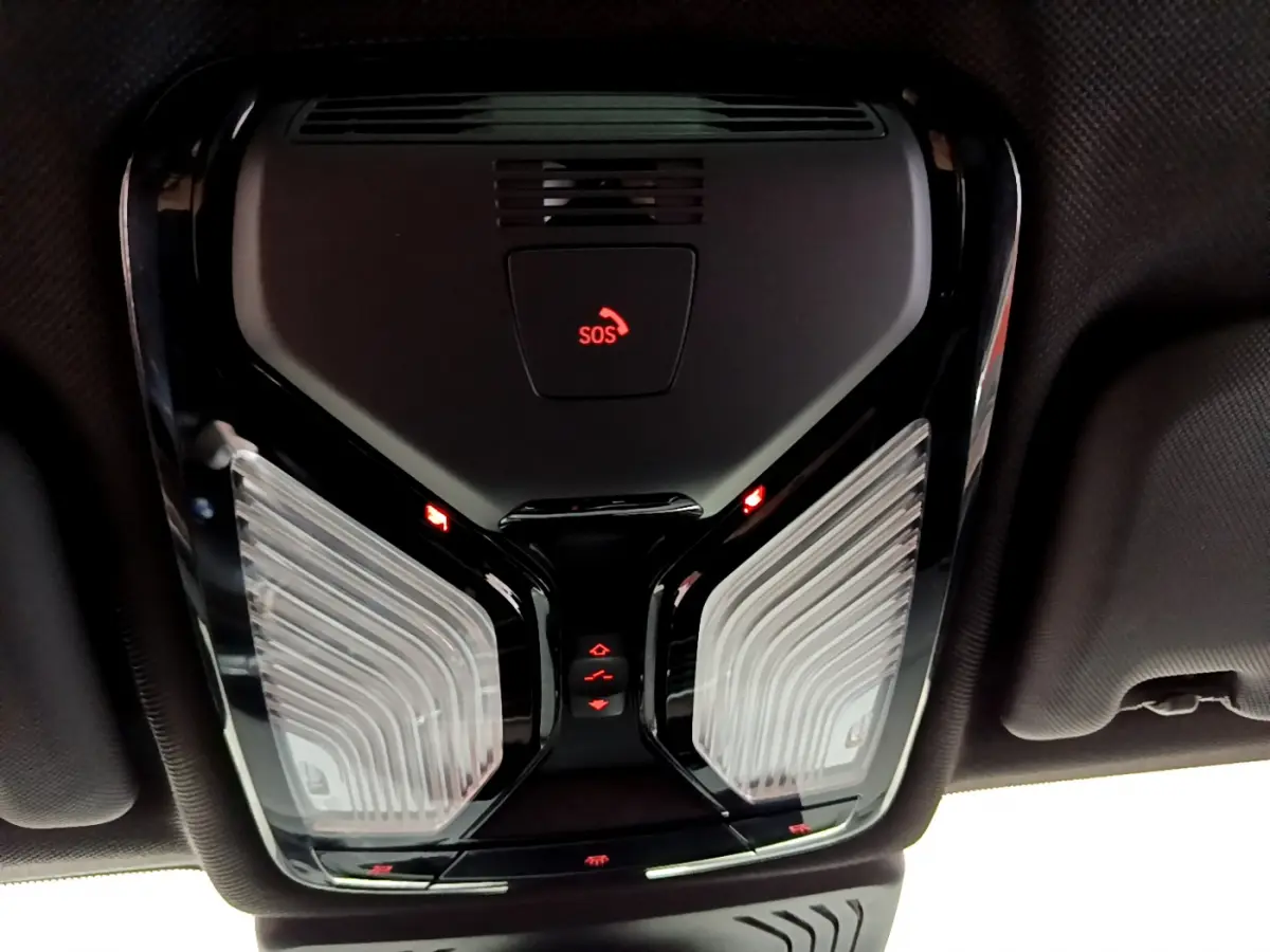 Vue en contre-plongée du plafonnier noir avec bouton SOS rouge allumé dans l’habitacle d’un BMW X3 noir.