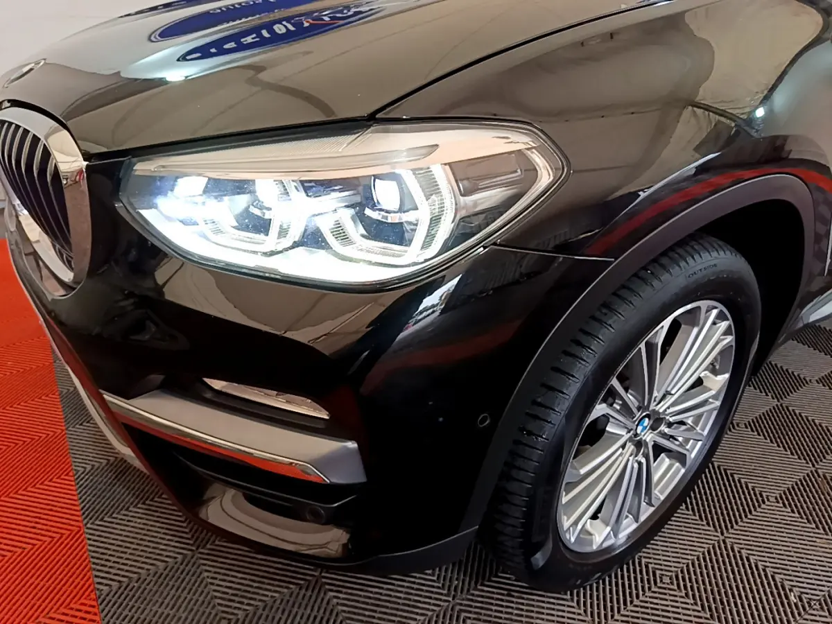 Gros plan sur l’avant droit noir brillant d’un BMW X3 2019 avec phare LED allumé et jante alliage visible.