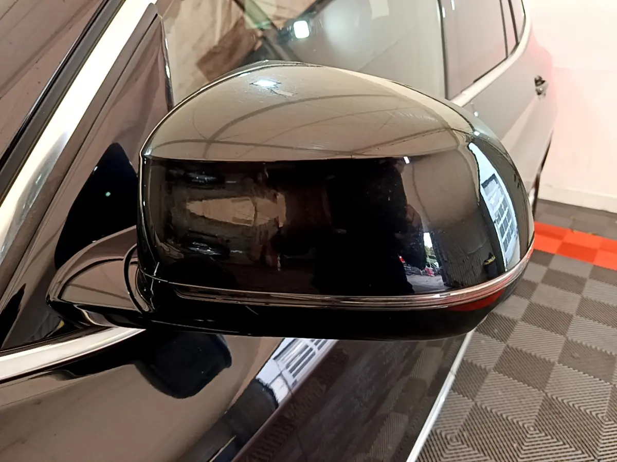Gros plan sur le rétroviseur côté gauche noir brillant d’un BMW X3 xDrive20d 2019, reflet de l’environnement intérieur visible.