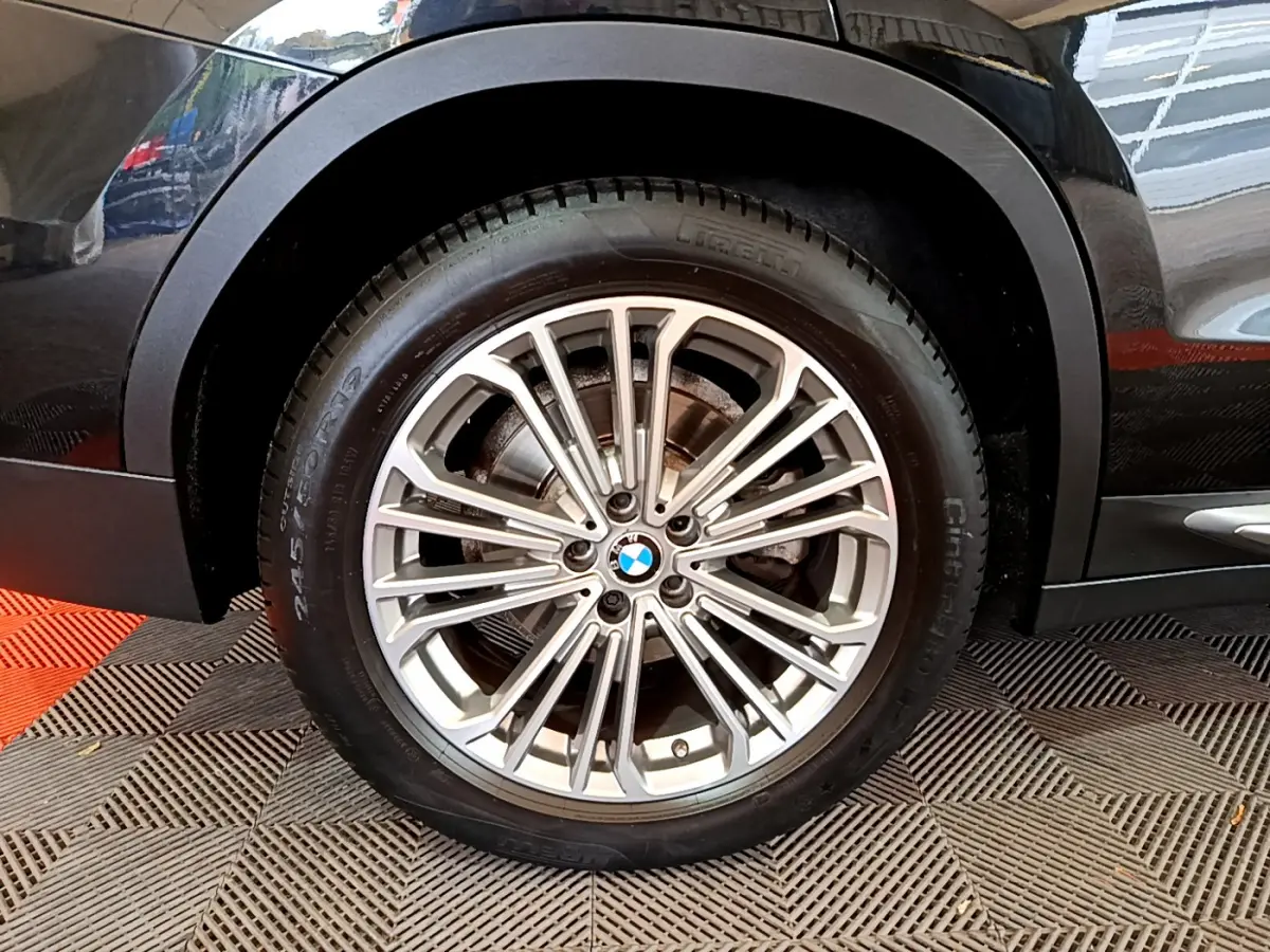 Gros plan sur la roue arrière droite d’un BMW X3 noir, mettant en valeur la jante alliage multi-branches et le logo BMW central.