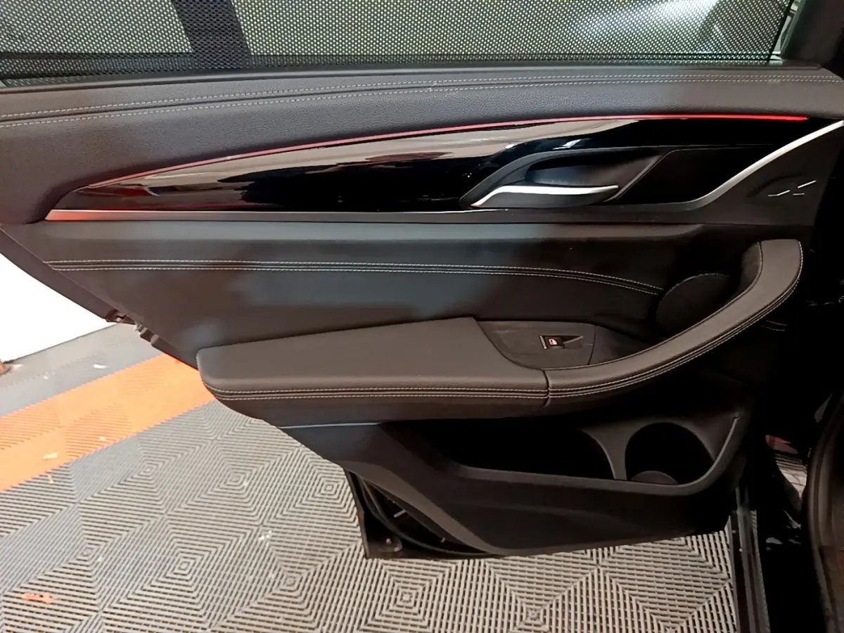 Gros plan sur la porte intérieure côté droit noire du BMW X3 xDrive20d 2019 avec surpiqûres blanches et insert laqué.