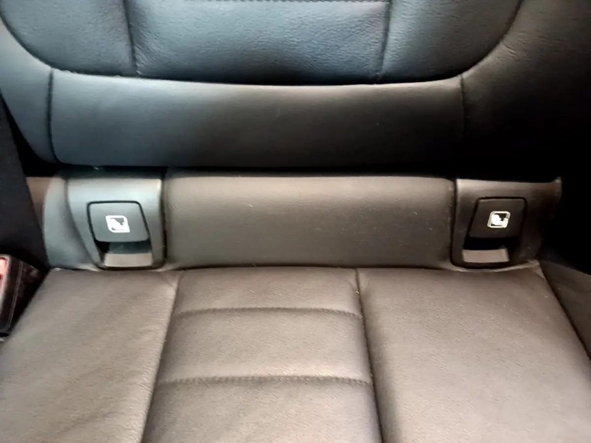 Gros plan sur la banquette arrière noire du BMW X3 avec boutons de rabattement des sièges intégrés.