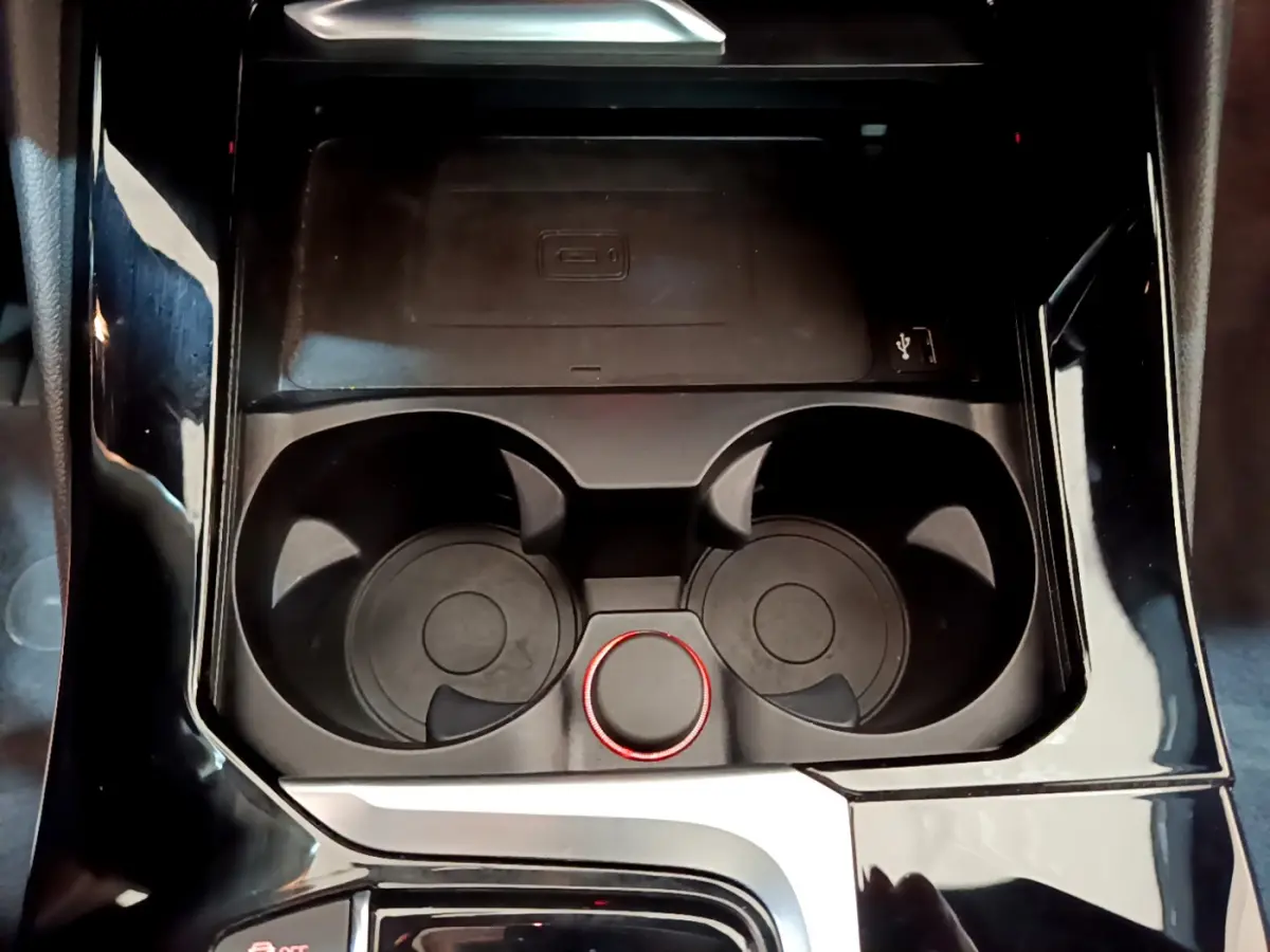 Gros plan sur la console centrale noire de la BMW X3 2019, avec porte-gobelets et molette de contrôle rouge.