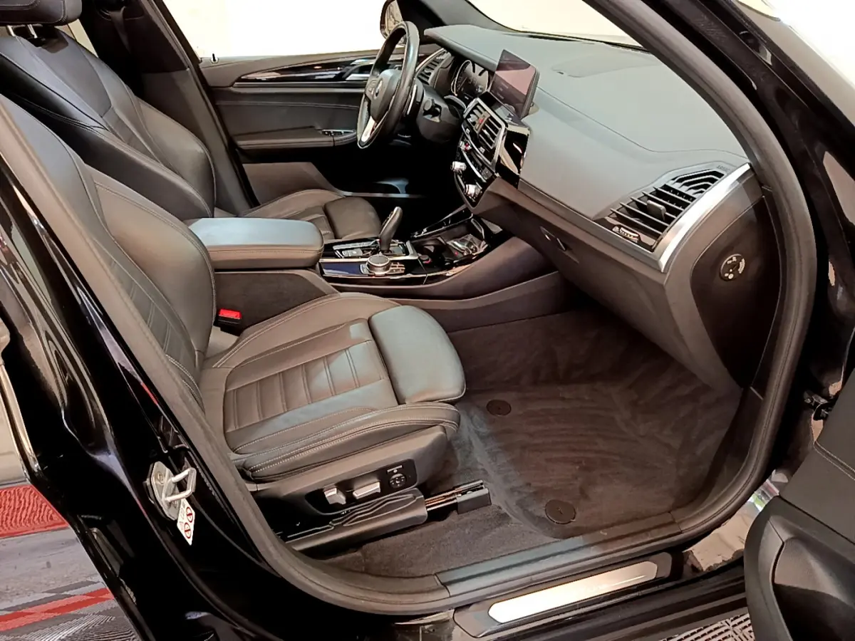 Vue intérieure côté conducteur du BMW X3 noir 2019, mettant en valeur les sièges cuir et le tableau de bord moderne.