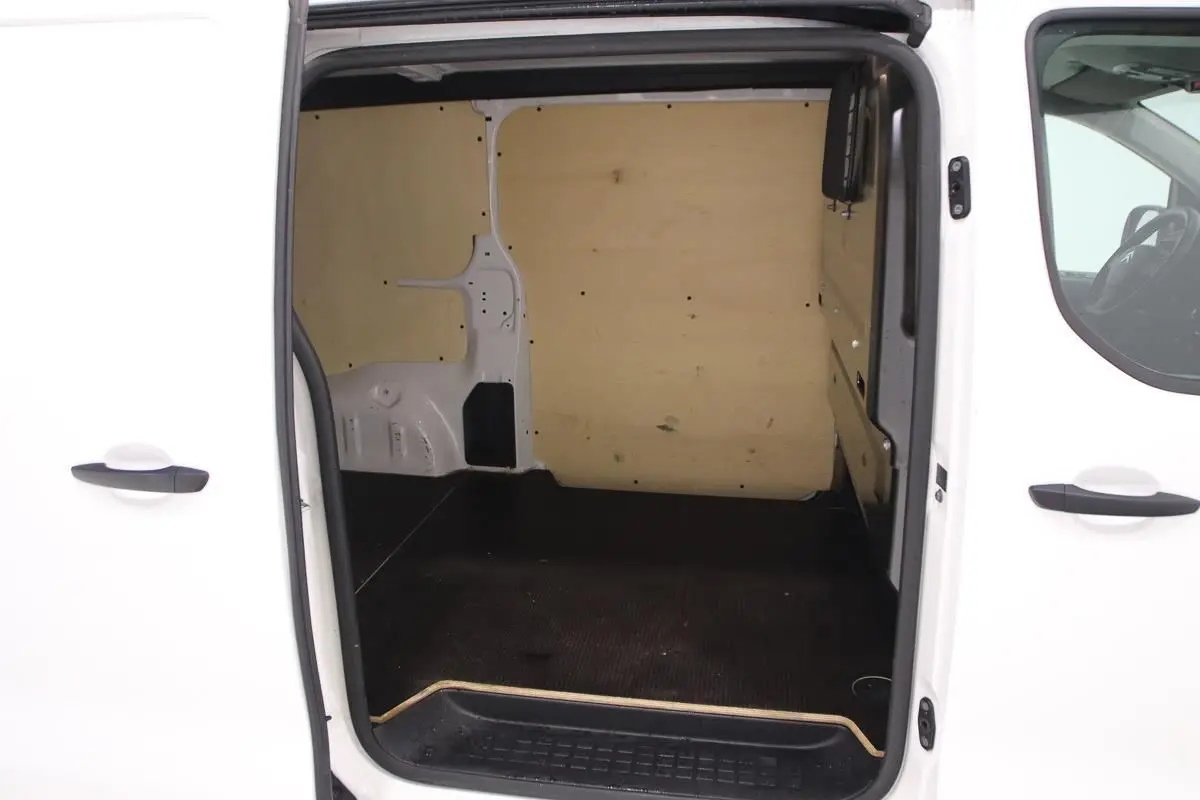 Vue intérieure par la porte latérale ouverte du Citroën Jumpy blanc, montrant l'aménagement bois du fourgon XL.