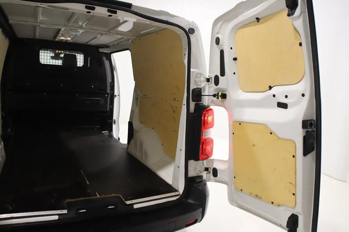 Vue arrière ouverte du fourgon blanc Citroën Jumpy XL 2019, montrant l'intérieur avec revêtement bois et plancher noir.