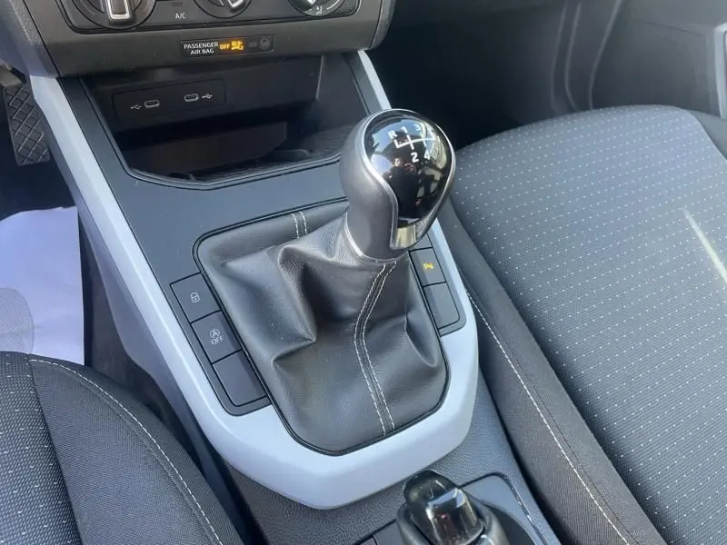 Gros plan sur le levier de vitesses manuel noir avec coutures blanches dans l'habitacle du SEAT Arona 2023 côté droit.