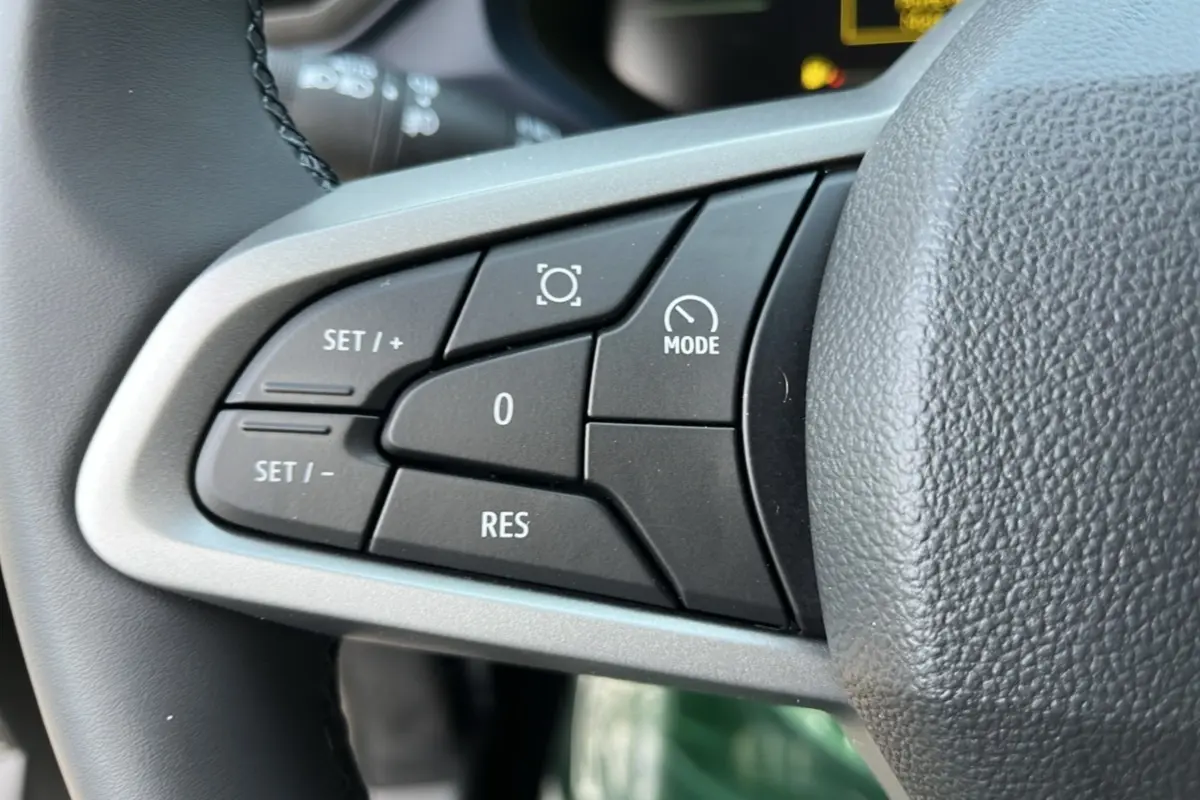 Gros plan sur les commandes de régulateur au volant cuir du Dacia Bigster Hybrid 155 Expression Plus, intérieur noir.