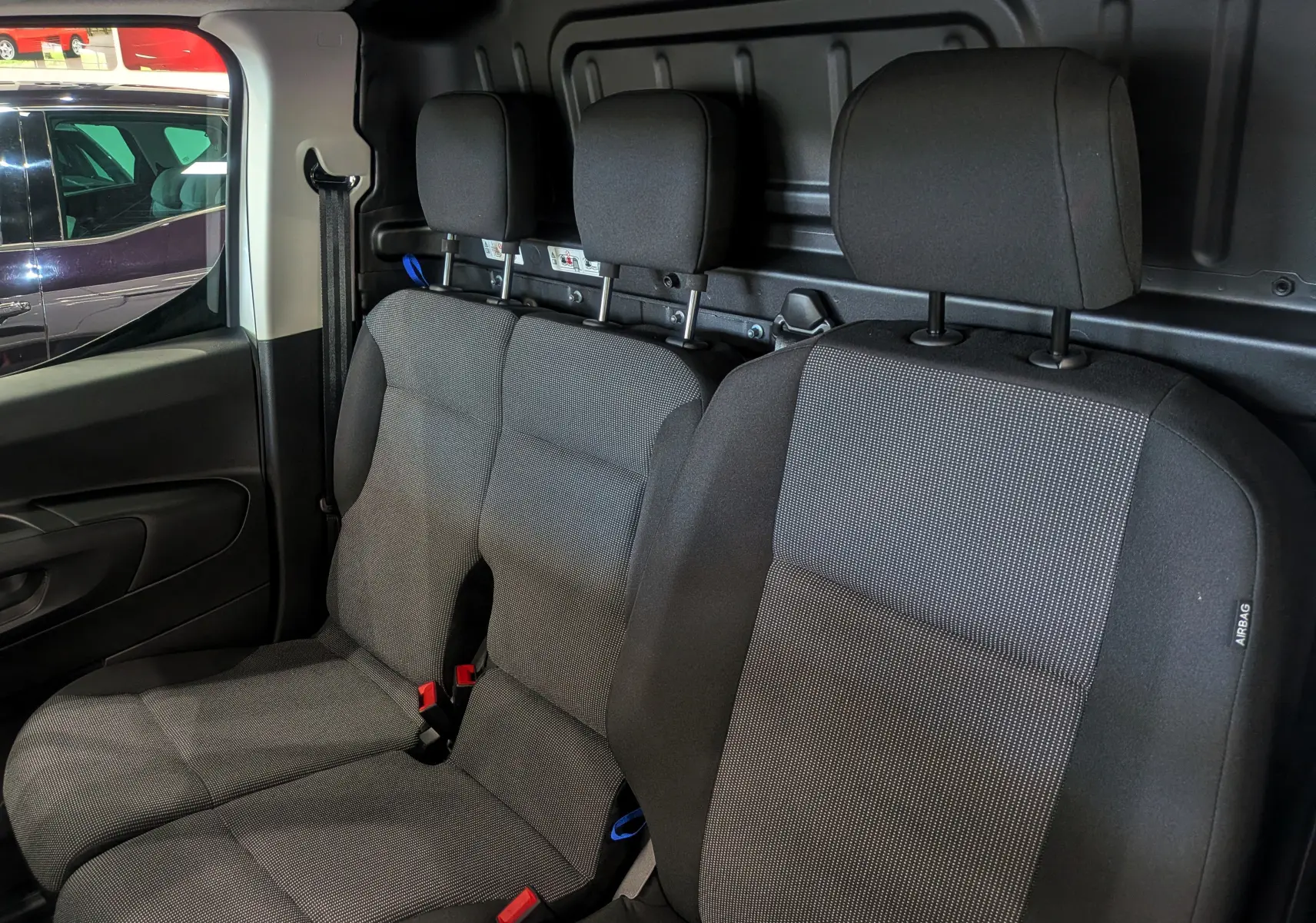 Vue intérieure des sièges avant en tissu gris foncé du Toyota Proace City Long 2026, avec appuie-têtes et ceinture visible côté gauche.